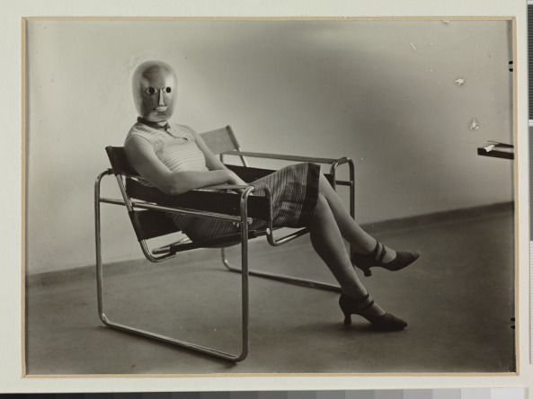 Lis Beyer or Ise Gropius sitting on the B3 club chair by Marcel Breuer and wearing a mask by Oskar Schlemmer and dress fabric by Lis Beyer, c. 1927.