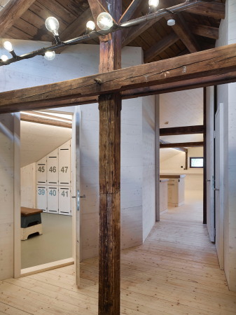 Eine raumhohe Tr, die die Form des Giebels aufnimmt, gliedert das Obergeschoss in Trainingsbereich und Clubraum. Steht sie offen, wird der Blick durch das gesamte Obergeschoss und in den Dachstuhl freigegeben.