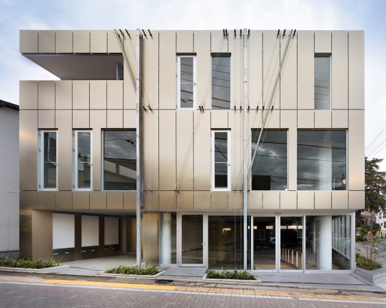 Die Fassade ist mit bronzefarbenen Aluminiumplatten verkleidet, die Dachentwsserung wird zum dekorativen Element.