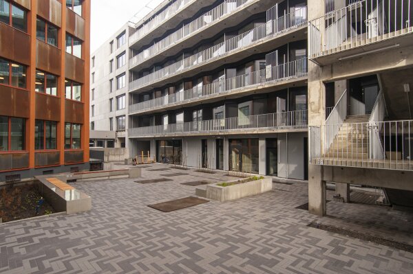 Im 1. Hof trifft der Neubau mit seinen Betonbalkonen auf die neue Corten-Stahl-Fassade des 1970er-Jahre-Gebudes (links)