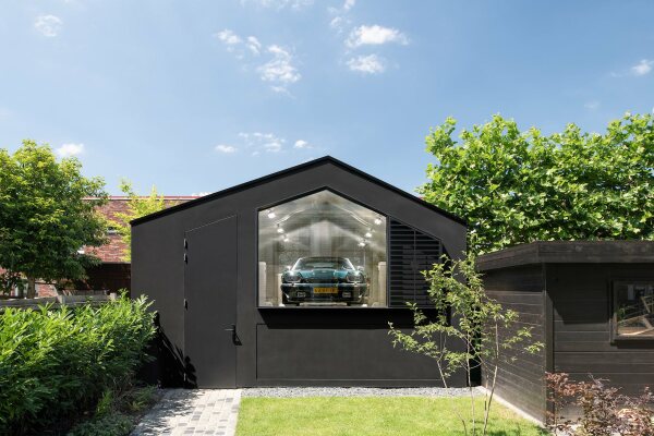 Der private Garagenshowroom im Garten imitiert ein schlichtes Gartenhuschen.