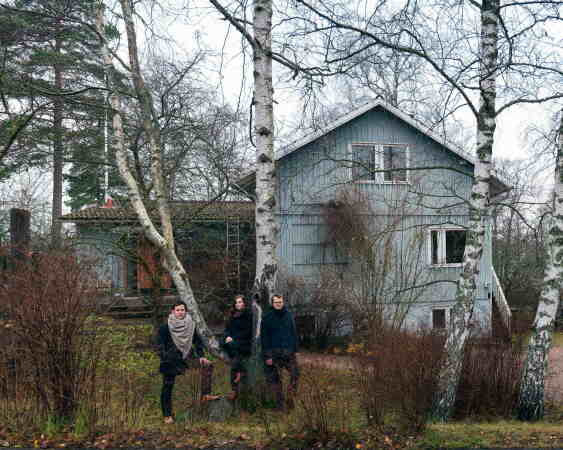 Die Kuratoren Laura Berger, Philip Tidwell und Kristo Vesikansa vor einem typischen Puutalo-Haus in Helsinki.