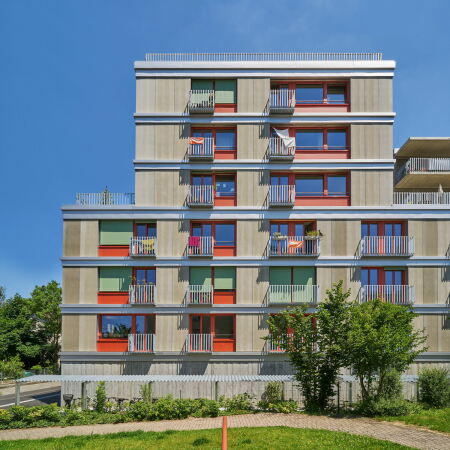 Eine Holzfassade und farbige Fensterelemente machen das uere Erscheinungsbild des hybriden Wohn-, Arbeits- und Universittsprojekts aus.