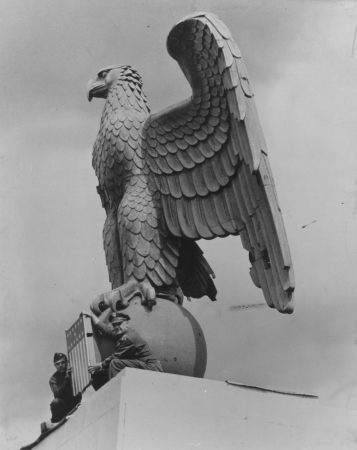 Amerikanische Soldaten verdecken das Hakenkreuz vor der Weltkugel des gusseisernen Adlers auf dem Flughafen Tempelhof mit dem zentralen Teil des amerikanischen Wappens, 12. Juni 1945.