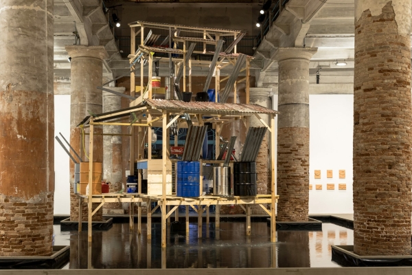 Daniel Otero Torres platzierte einen pltschernen Brunnen zwischen den Sulen. Oder ist es ein Haus? Die Konstruktion erinnert an Flugemeinden in Kolumbien, die Regenwasser sammeln mssen, weil der illegale Goldabbau die Quellen verseucht.