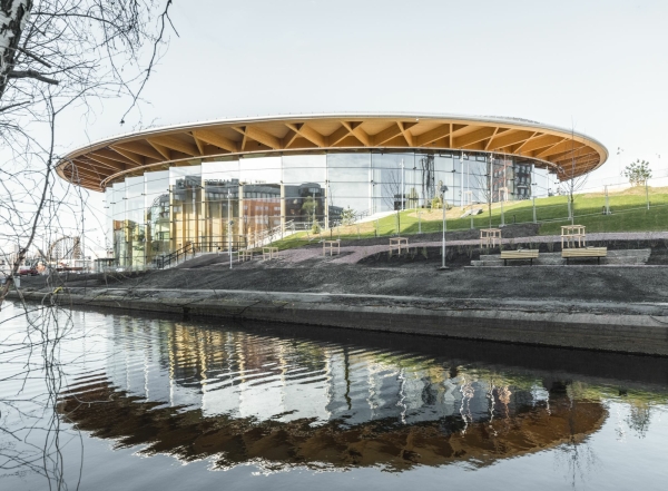 Das Holzdach des Gebudes kragt weit ber die glserne Fassade aus.