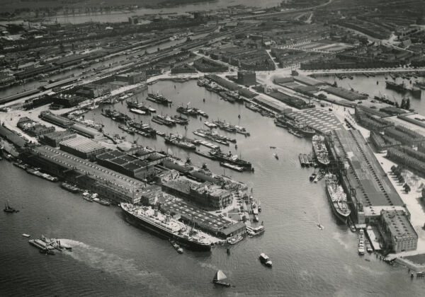 Historische Luftaufnahme des Rijnhaven. Das San Francisco-Lagerhaus befindet sich am rechten Bildrand. In der Bildmitte das berhmte Hotel New York. Ganz links am Bildrand der Standort von OMAs Hochhaus De Rotterdam.